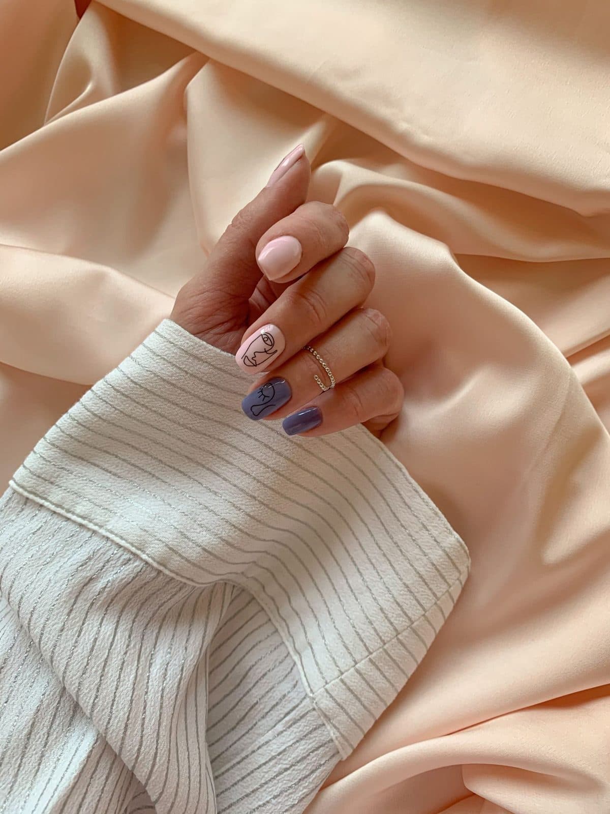Mano con uñas decoradas sobre satín color durazno